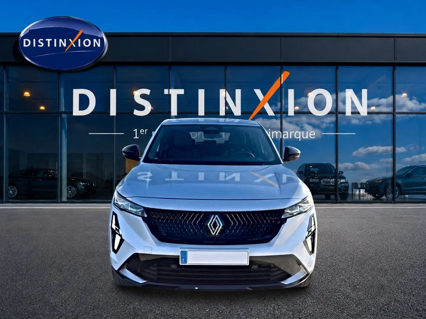 Vue de face d'une Renault Rafale blanche 2025 avec calandre noire et feux LED distinctifs, devant une vitrine Distinxion.