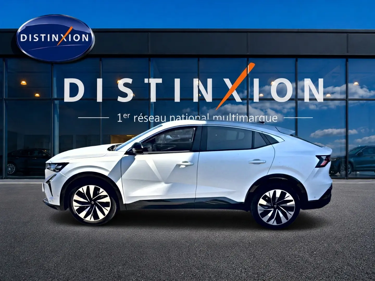 Renault Rafale blanc en profil droit, SUV coupé avec jantes noires et blanches, devant vitrine Distinxion.