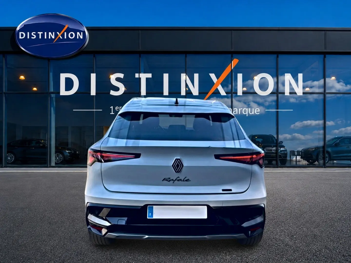 Vue arrière d'une Renault Rafale blanche 2025 garée devant une vitrine avec logo Distinxion.