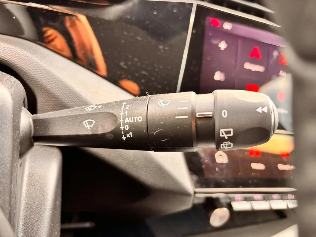 Gros plan sur la commande d’essuie-glace côté gauche du tableau de bord d’une Peugeot 308 gris 2025 Hybrid Allure.