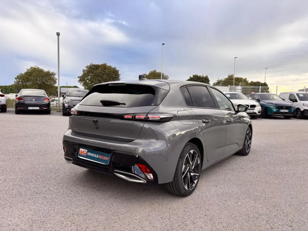 Vue 3/4 arrière droite d'une Peugeot 308 gris métallisé avec jantes alliage 17 pouces et vitres teintées.