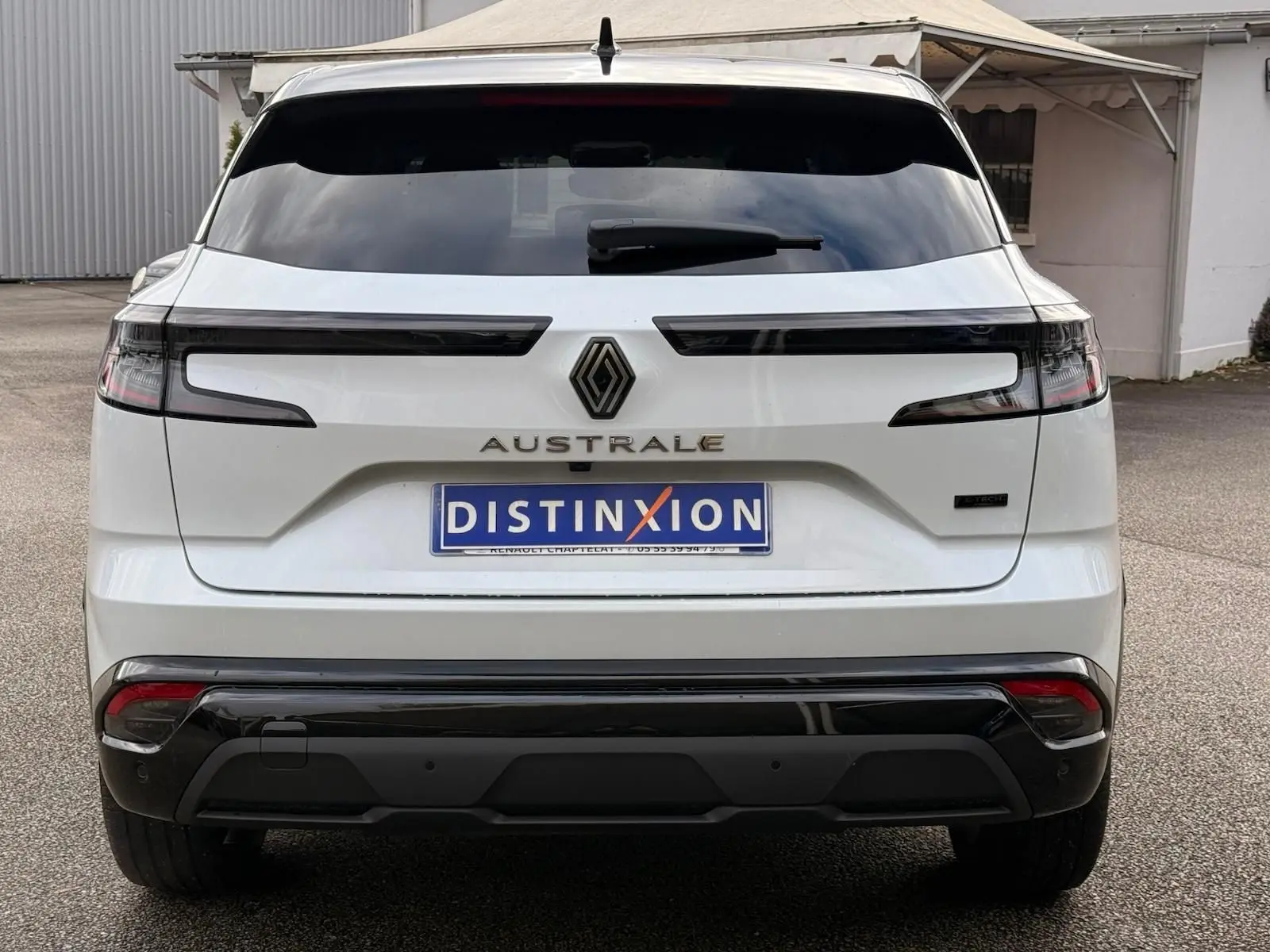 Vue arrière d'un Renault Austral blanc nacré avec toit noir, mettant en valeur ses feux horizontaux et son logo central.
