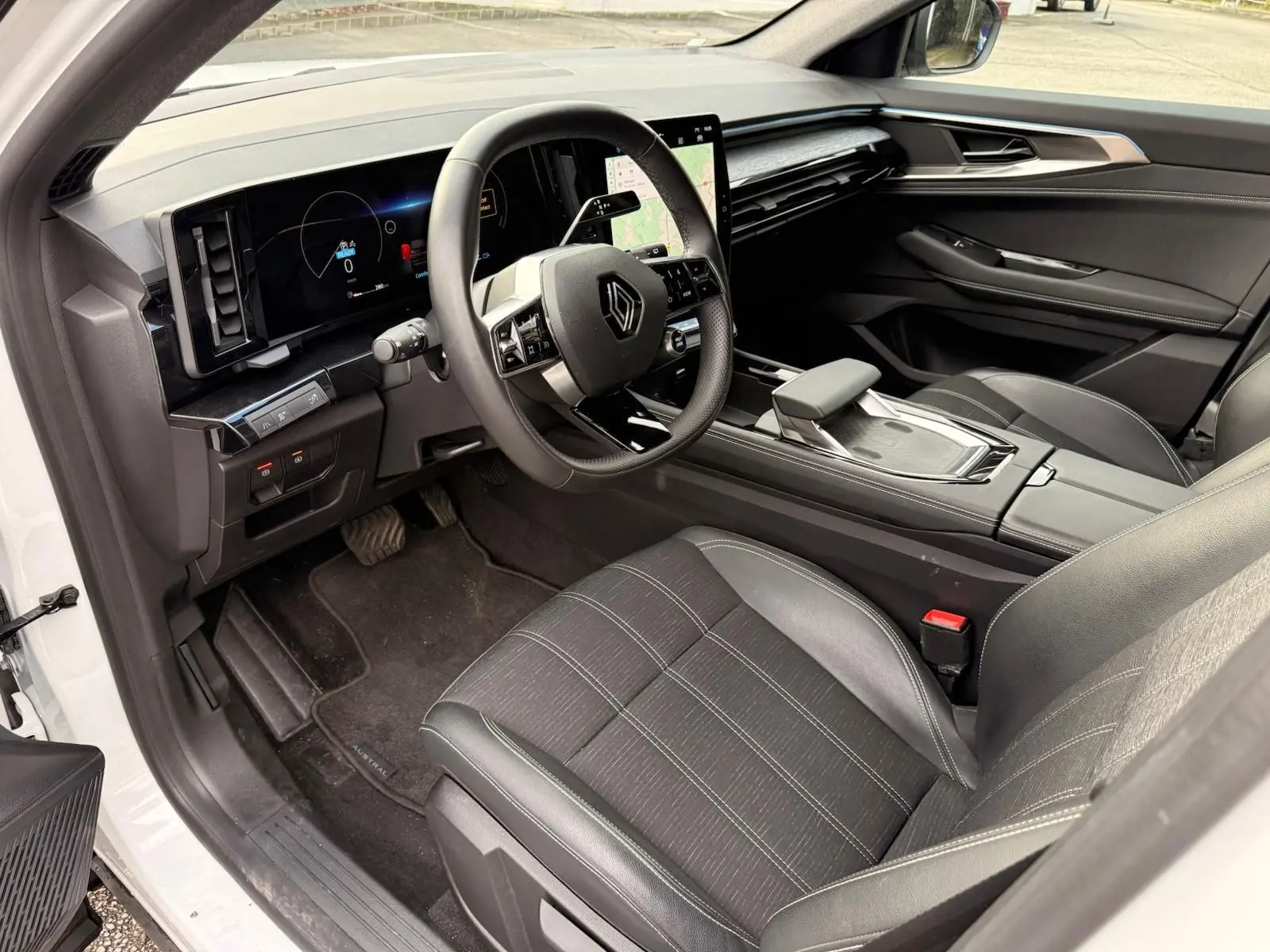 Intérieur du Renault Austral E-Tech 200 hybride, vue côté conducteur, avec tableau de bord numérique et sièges noirs en tissu et cuir.