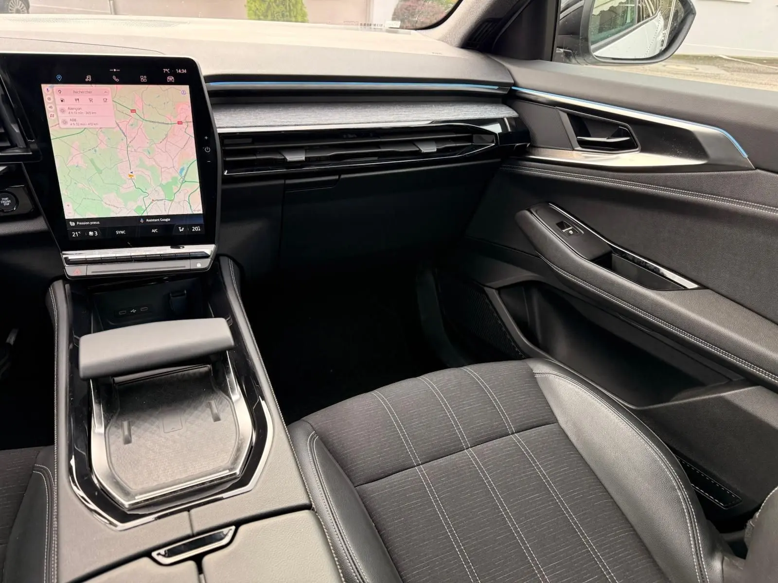Vue intérieure côté passager du tableau de bord et console centrale du Renault Austral E-Tech 200 blanc nacré avec écran tactile et sellerie noire.