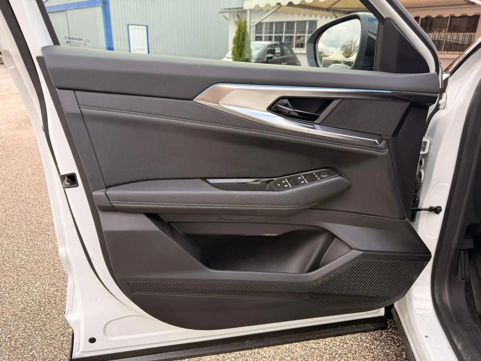 Intérieur côté gauche de la porte avant d'une Renault Austral 2023 blanc nacré avec garniture noire et commandes électriques.