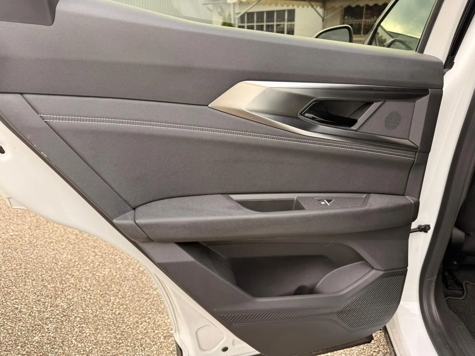 Vue intérieure de la porte arrière droite du Renault Austral E-Tech blanc nacré avec garniture noire et surpiqûres grises.