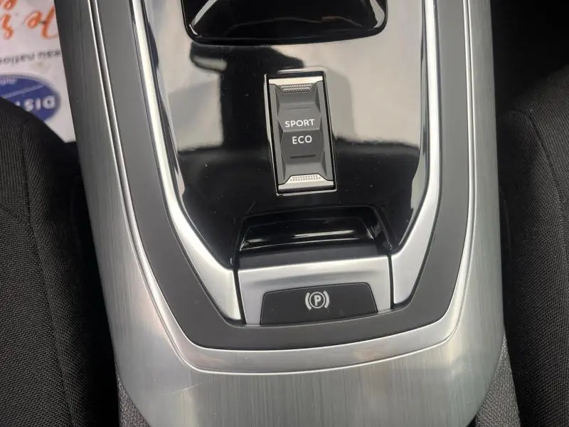 Gros plan sur la console centrale de la Peugeot 308 blanche, avec bouton mode Sport/Eco et frein à main électrique.