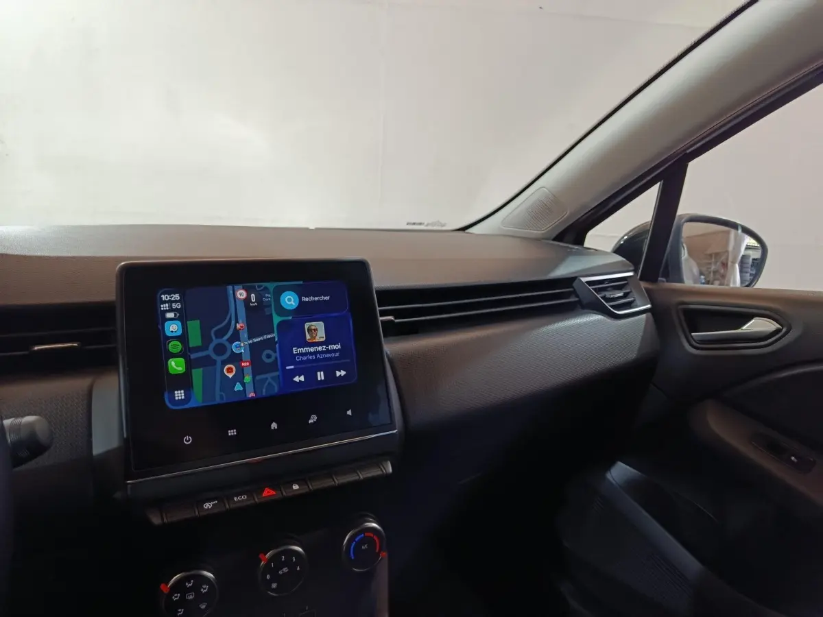 Vue intérieure côté passager de la Renault Clio gris clair 2023, avec écran tactile central affichant navigation et musique.