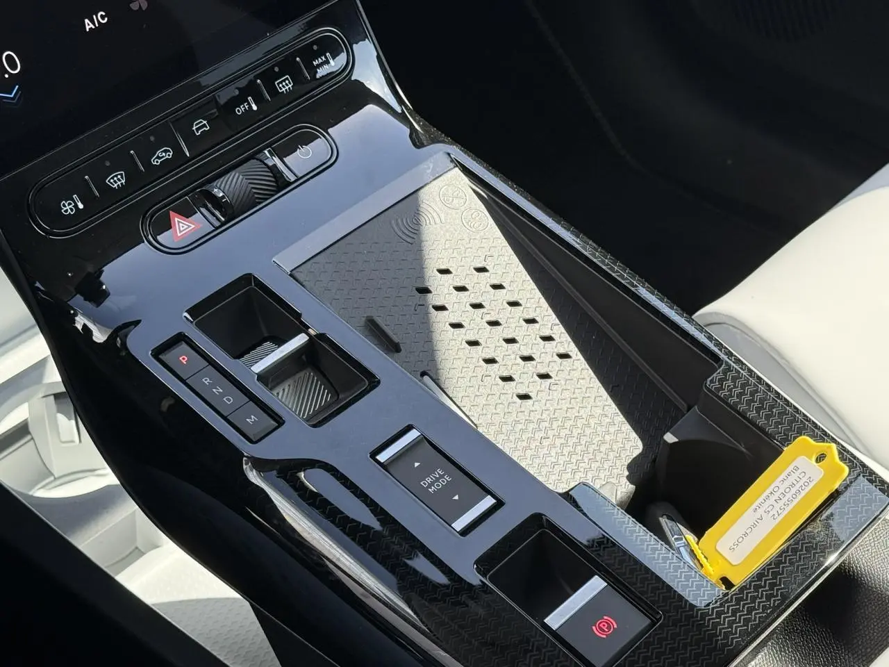 Vue rapprochée de la console centrale noire brillante du Citroën C5 Aircross blanc, avec commandes de boîte auto et mode de conduite.