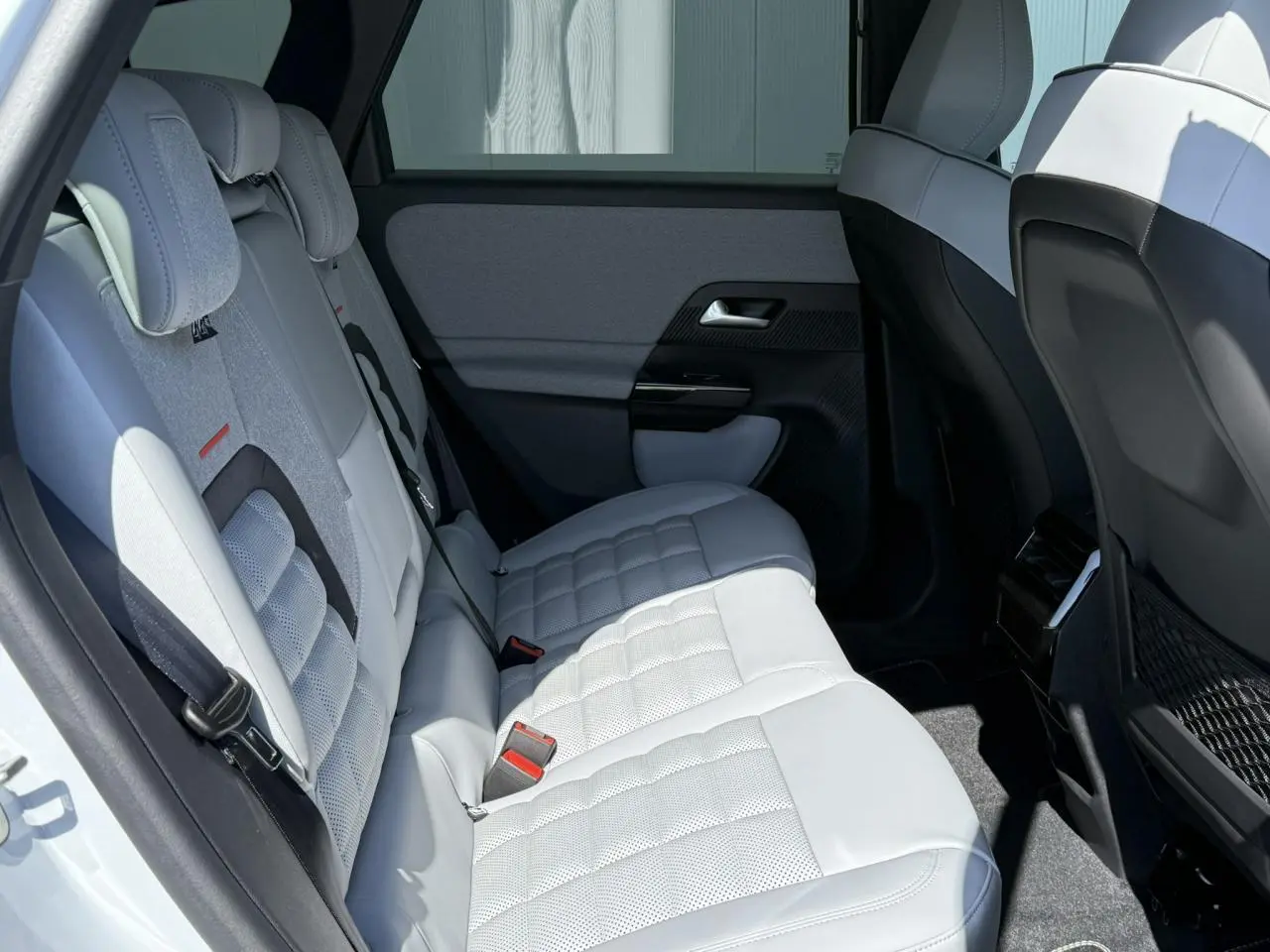 Vue latérale droite de la banquette arrière blanche et grise du Citroën C5 Aircross 2025 avec appuie-têtes et filets de rangement.