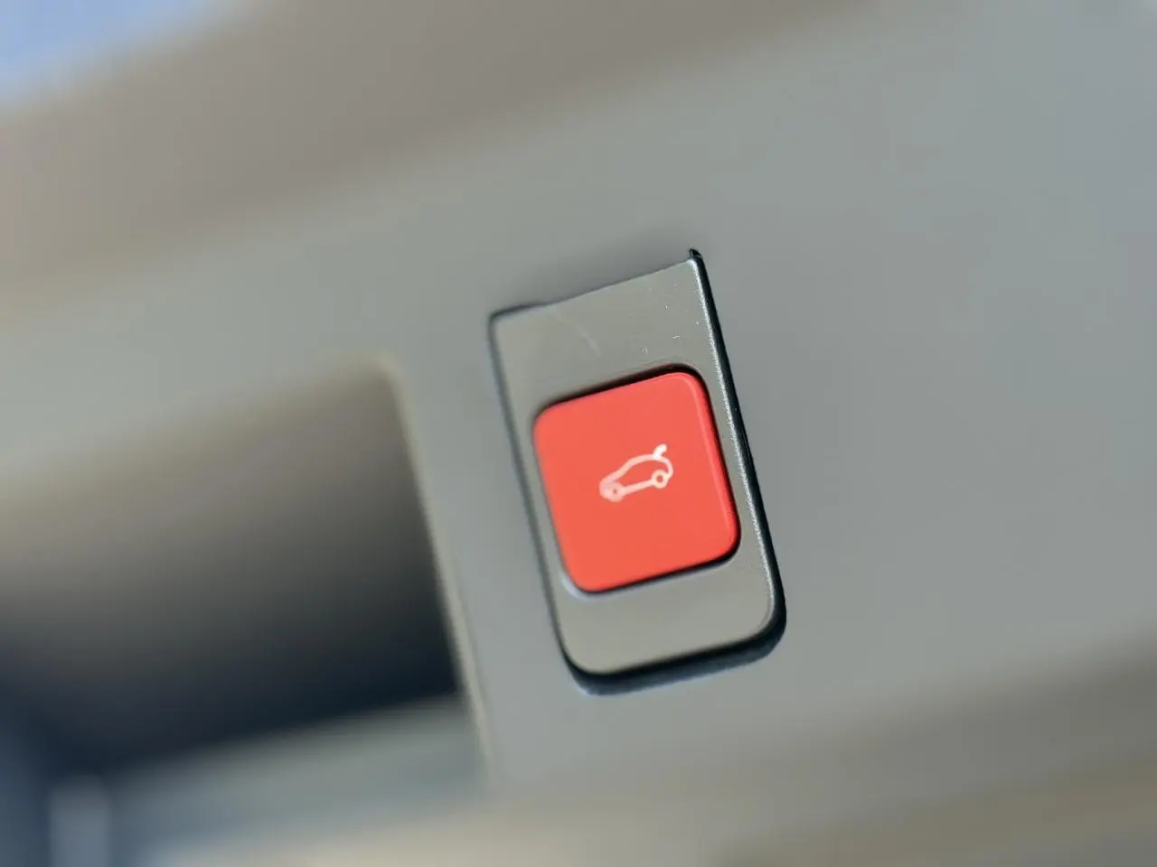 Bouton rouge d'ouverture électrique du hayon sur un véhicule Citroën C5 Aircross blanc, vue en gros plan.