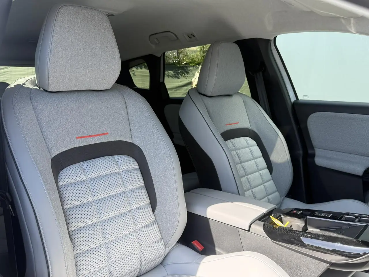 Vue intérieure des sièges avant gris clair avec inserts textiles et accoudoir central du Citroën C5 Aircross 2025.