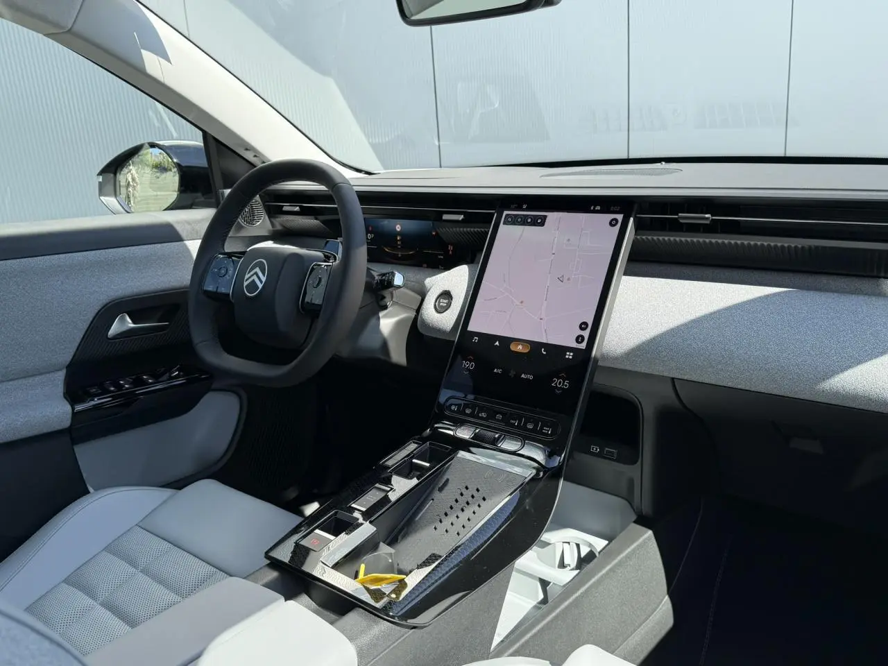 Vue intérieure côté conducteur du Citroën C5 Aircross 2025, tableau de bord clair avec écran tactile vertical et sellerie grise.
