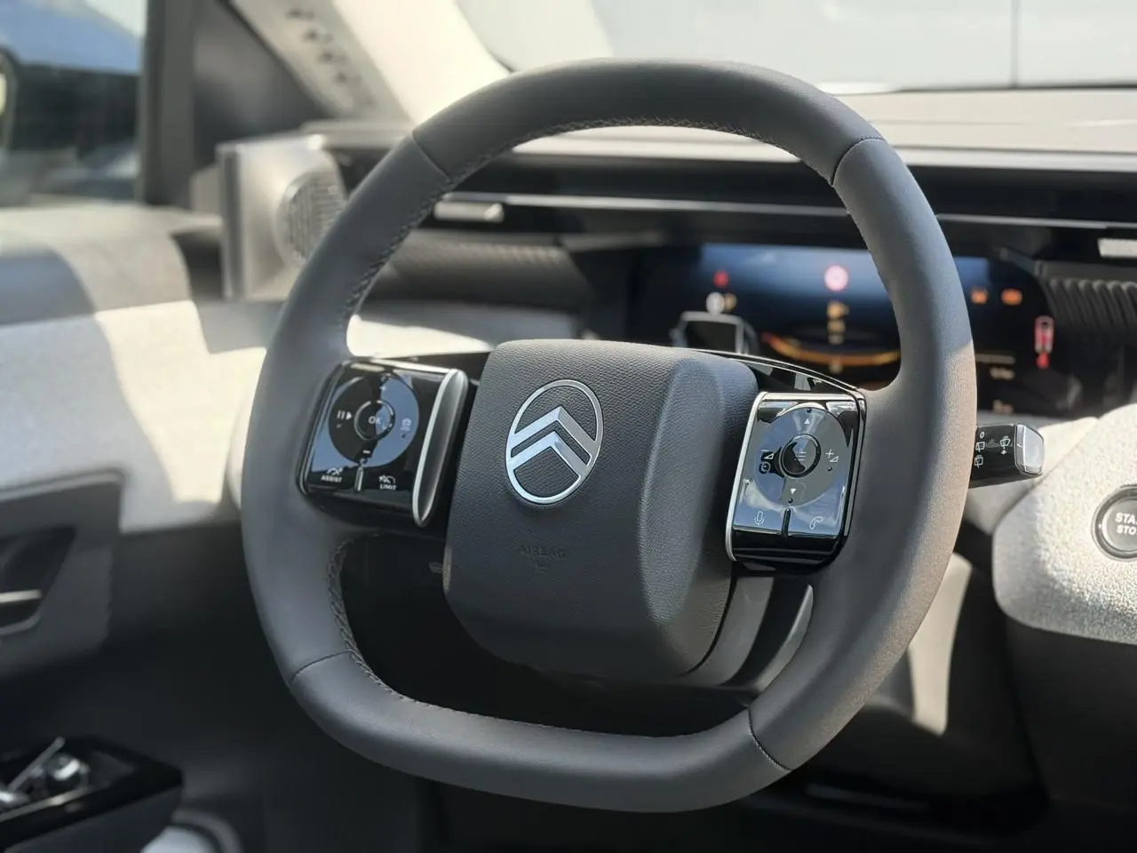 Vue rapprochée du volant noir multifonctions du Citroën C5 Aircross 2025 avec tableau de bord numérique en arrière-plan.