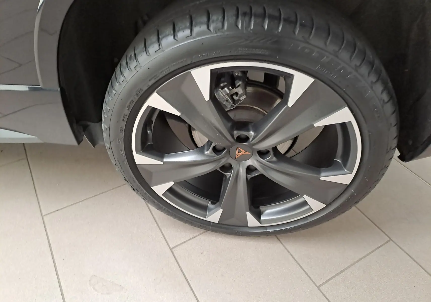 Gros plan sur la roue avant gauche du CUPRA Ateca 2024 noir magique, mettant en valeur la jante alliage bicolore et le logo CUPRA central.