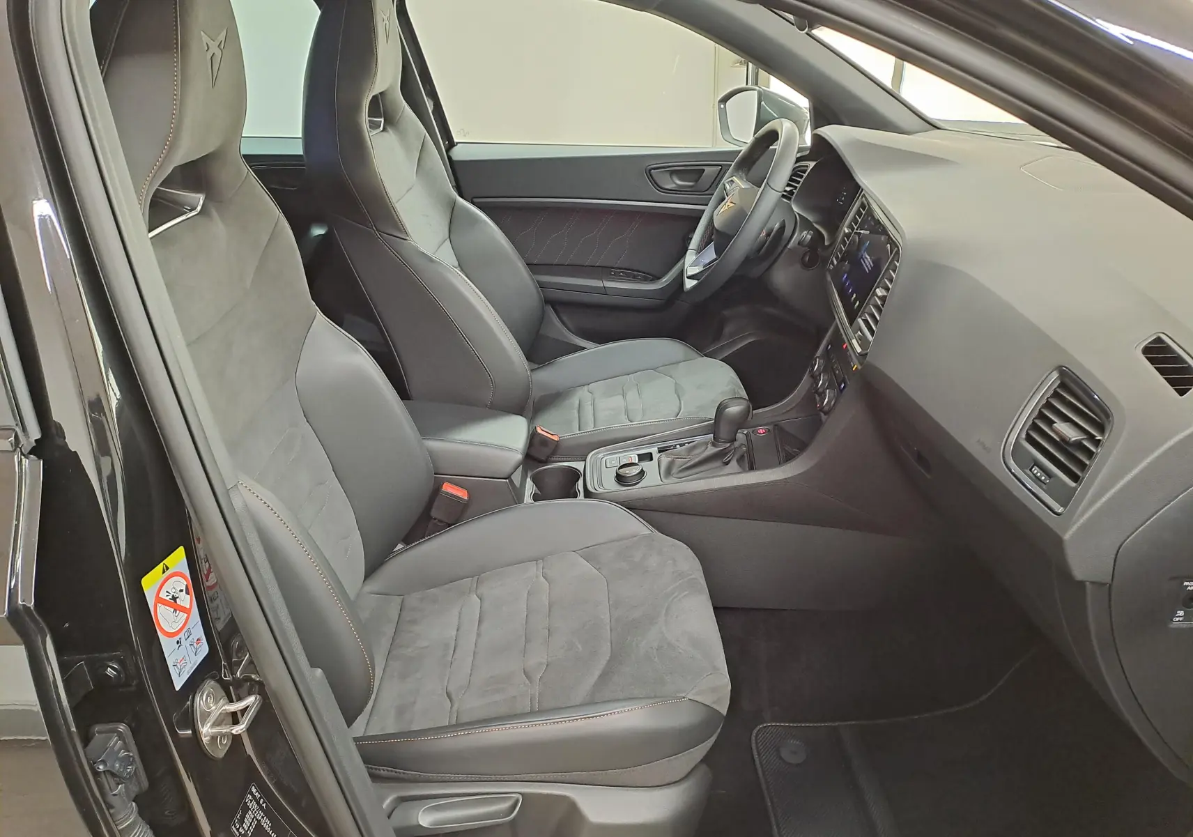 Vue intérieure côté conducteur du CUPRA Ateca 2024 noir magique, sièges sport en alcantara avec surpiqûres orange.