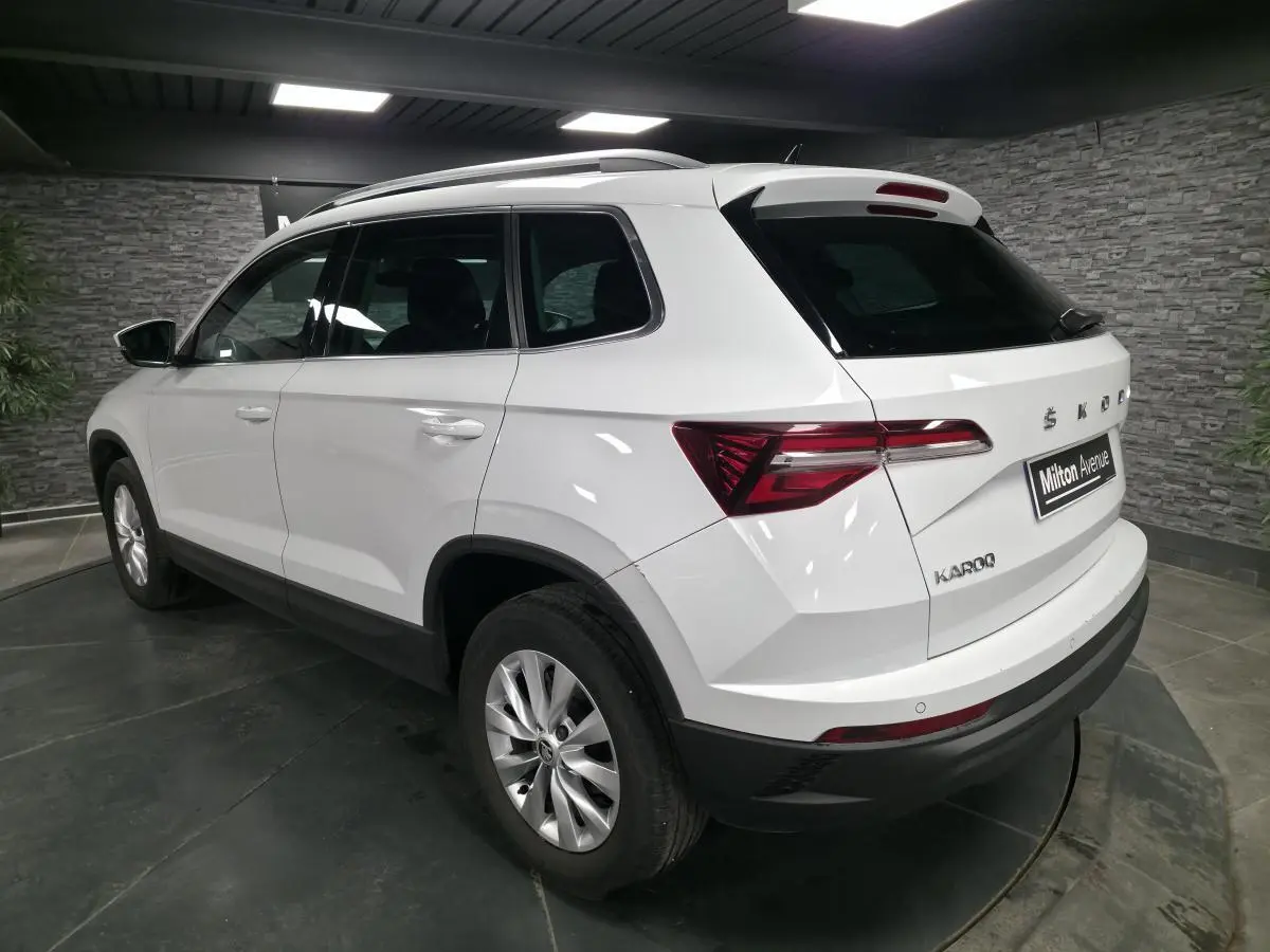 Vue 3/4 arrière droite d'un SUV SKODA KAROQ blanc avec feux arrière LED et jantes alliage 16 pouces.