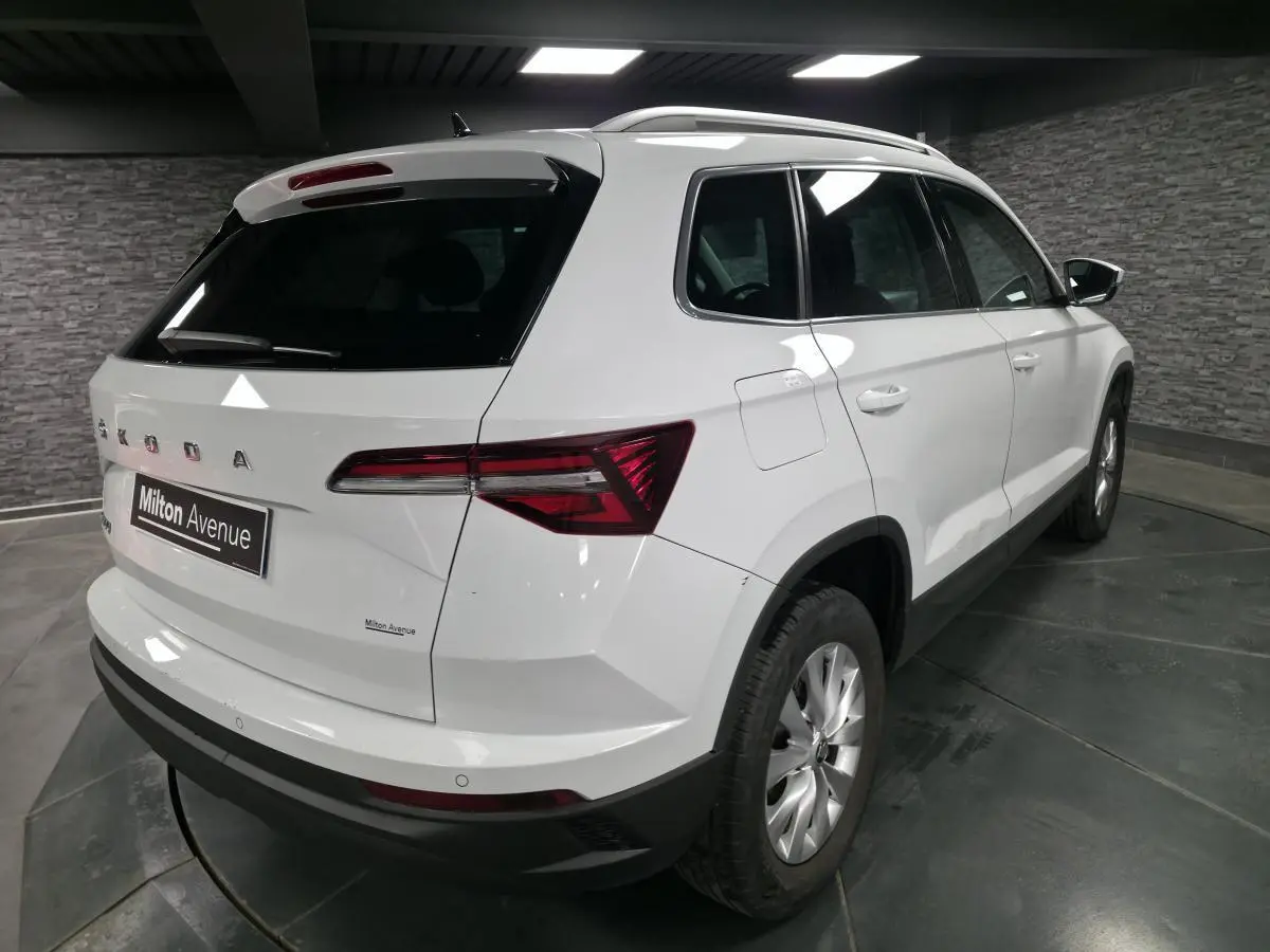 Vue 3/4 arrière droite d'un SUV Skoda Karoq blanc avec feux arrière LED et jantes alliage 16 pouces.
