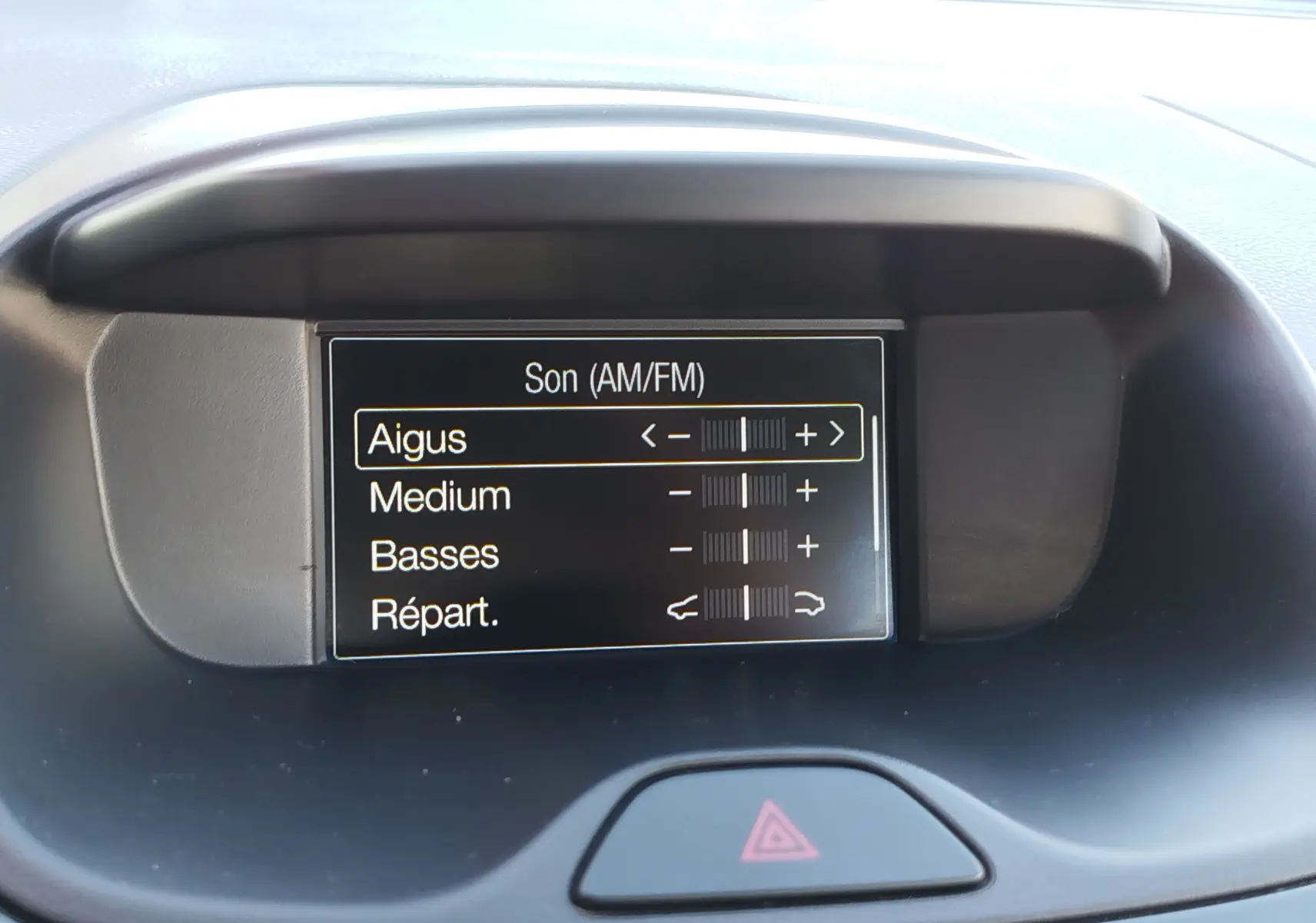 Écran central du tableau de bord du Ford KA+ 2020, affichant les réglages audio avec bouton de signal d’alerte en dessous.