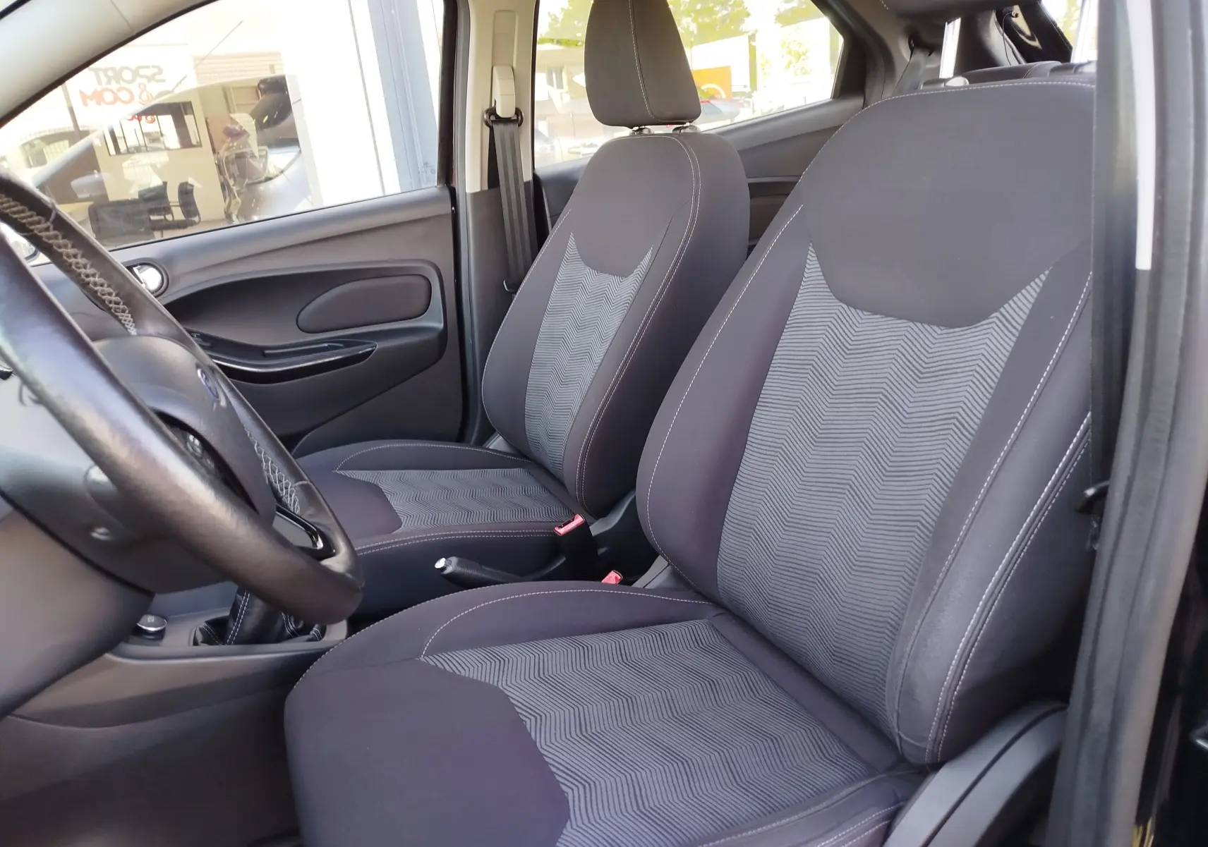 Vue intérieure côté conducteur du Ford KA+ 2020, sièges tissu gris avec motifs et volant cuir noir.