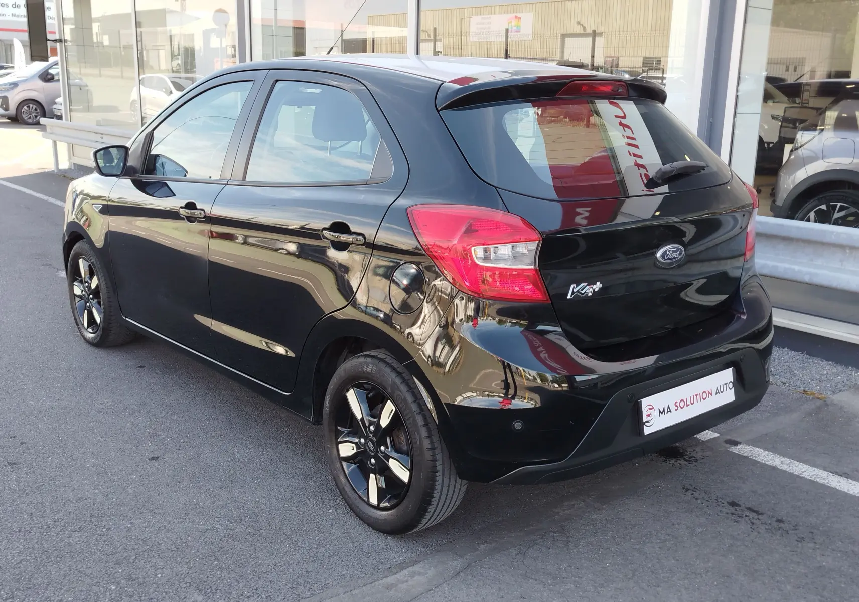 Vue 3/4 arrière droite d'une Ford KA+ noire Shadow avec toit blanc, jantes noires et feux arrière rouges.