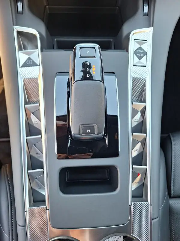 Vue plongeante sur la console centrale grise du DS7 BlueHDi 130 EAT8 2025, avec levier de vitesse automatique et boutons triangulaires.