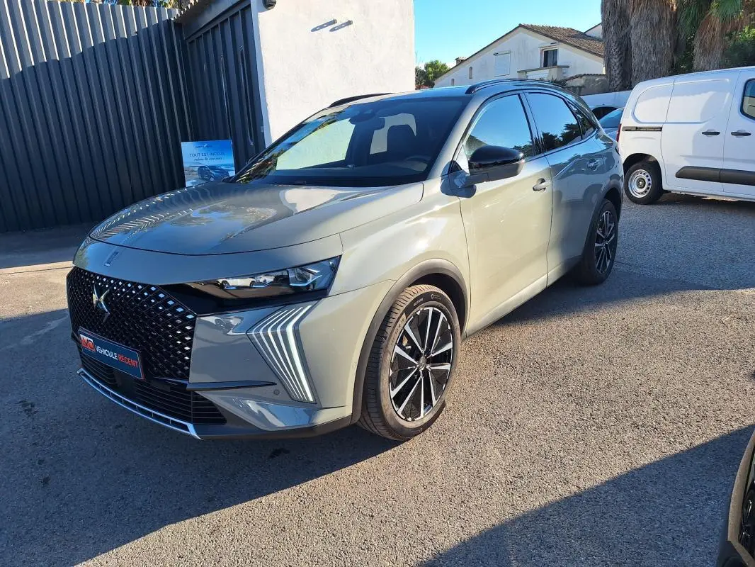 DS7 BlueHDi 130 EAT8 gris vu en 3/4 avant droit, avec calandre noire à motifs et feux LED distinctifs en forme de flèche.