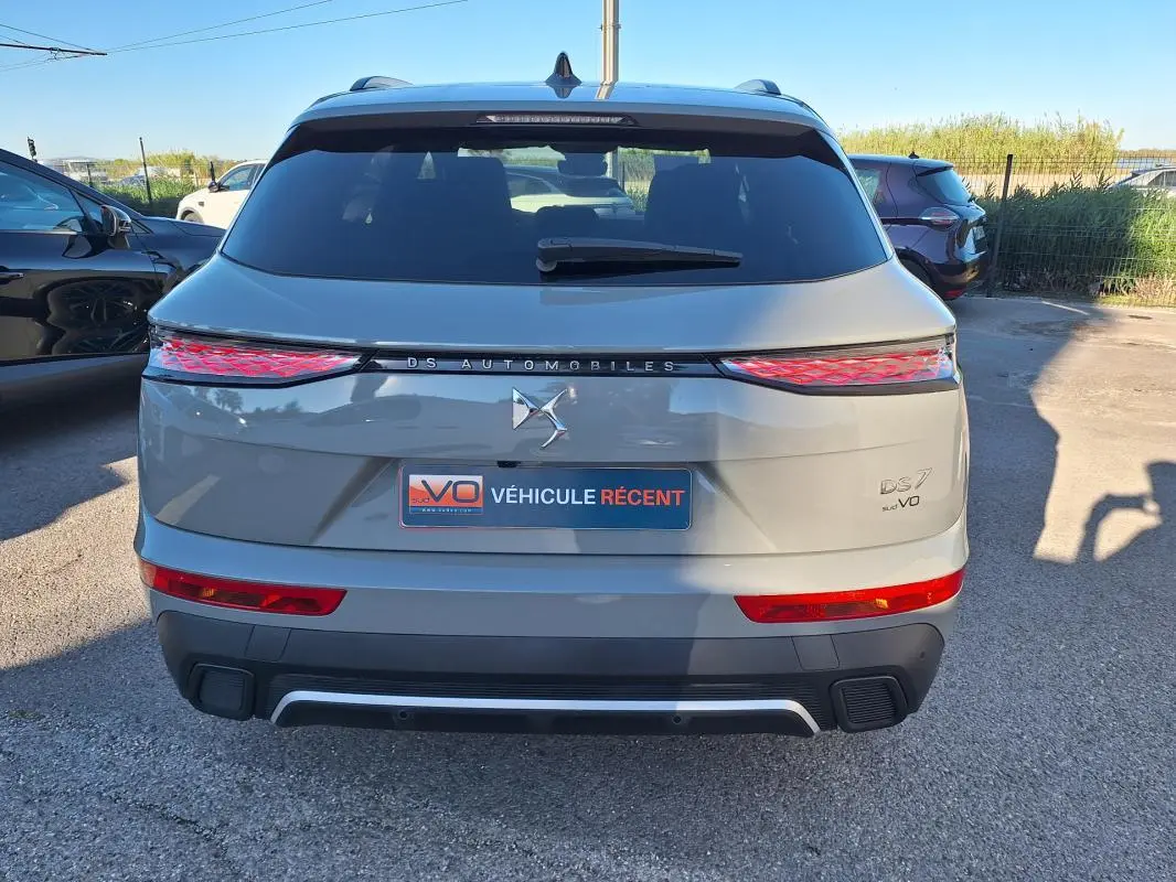 Vue arrière d'un DS7 gris 2025 avec feux arrière allongés et logo DS Automobiles au centre.