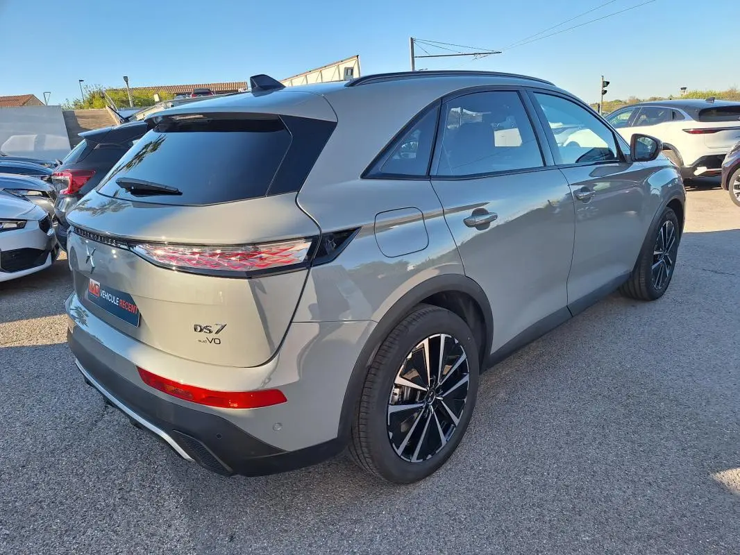 Vue 3/4 arrière droite du SUV DS7 gris 2025 avec feux arrière distinctifs et jantes noires bicolores.