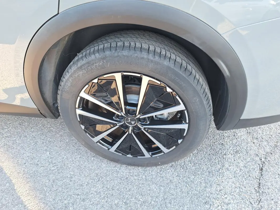Gros plan sur la roue avant gauche du DS7 2025 gris, avec jante noire et argentée au design géométrique distinctif.
