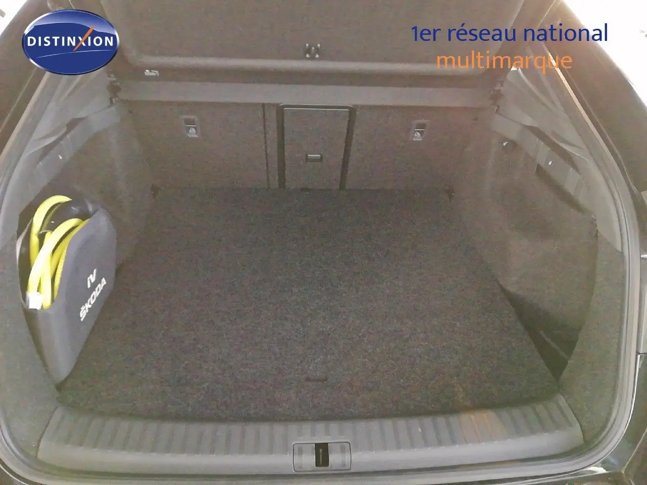 Coffre ouvert vu de l'arrière d'une Skoda Enyaq Coupé noire métal avec sac de câble de recharge électrique.