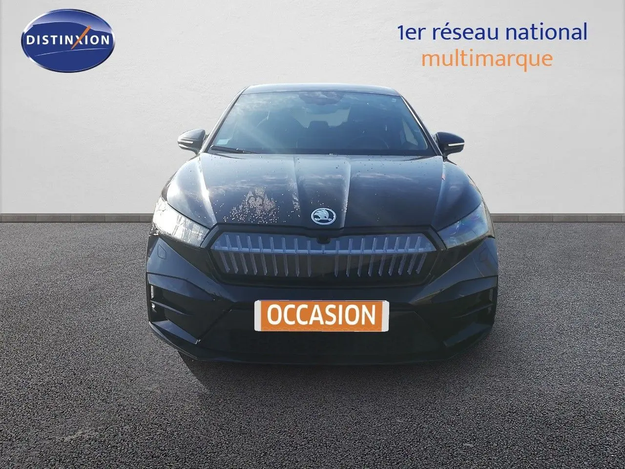 Vue frontale d'une Skoda Enyaq noire métal électrique avec calandre marquée et logo au centre.