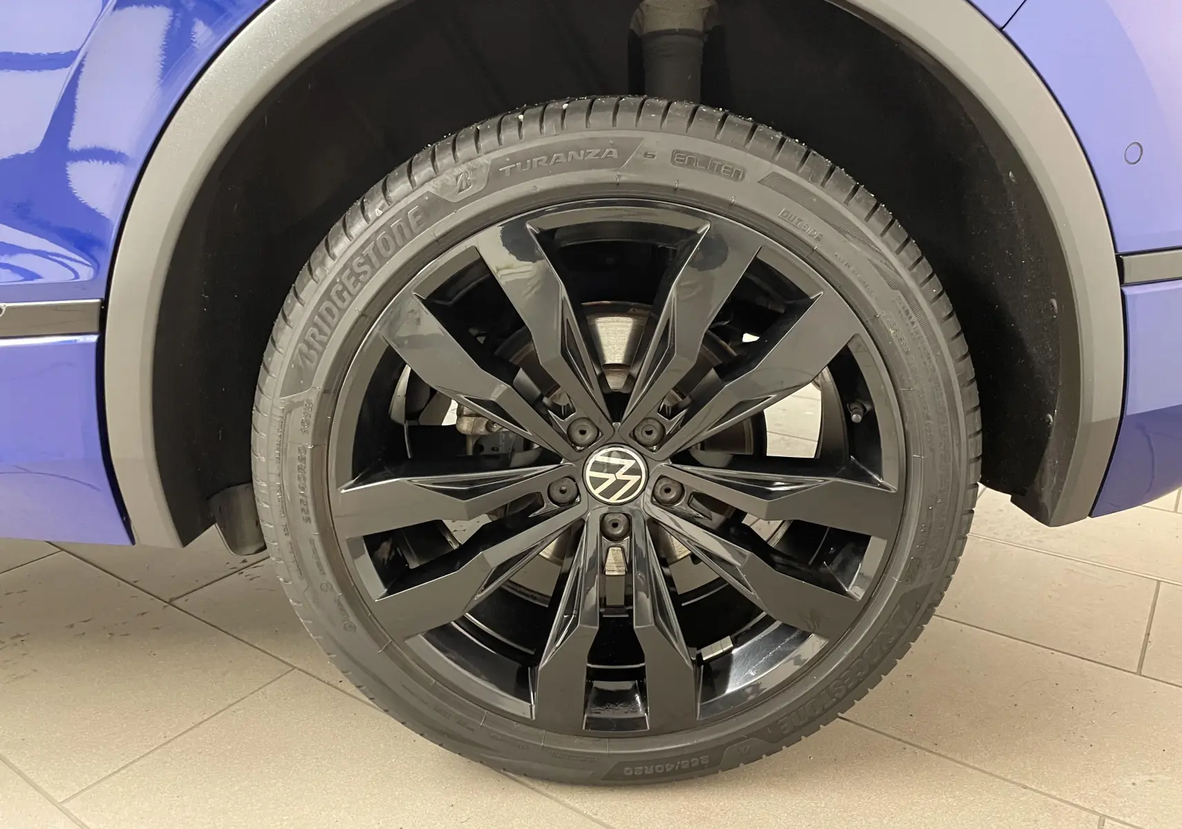 Gros plan sur la jante noire 20'' Suzuka du Volkswagen Tiguan Bleu Lapiz, côté arrière droit du véhicule.