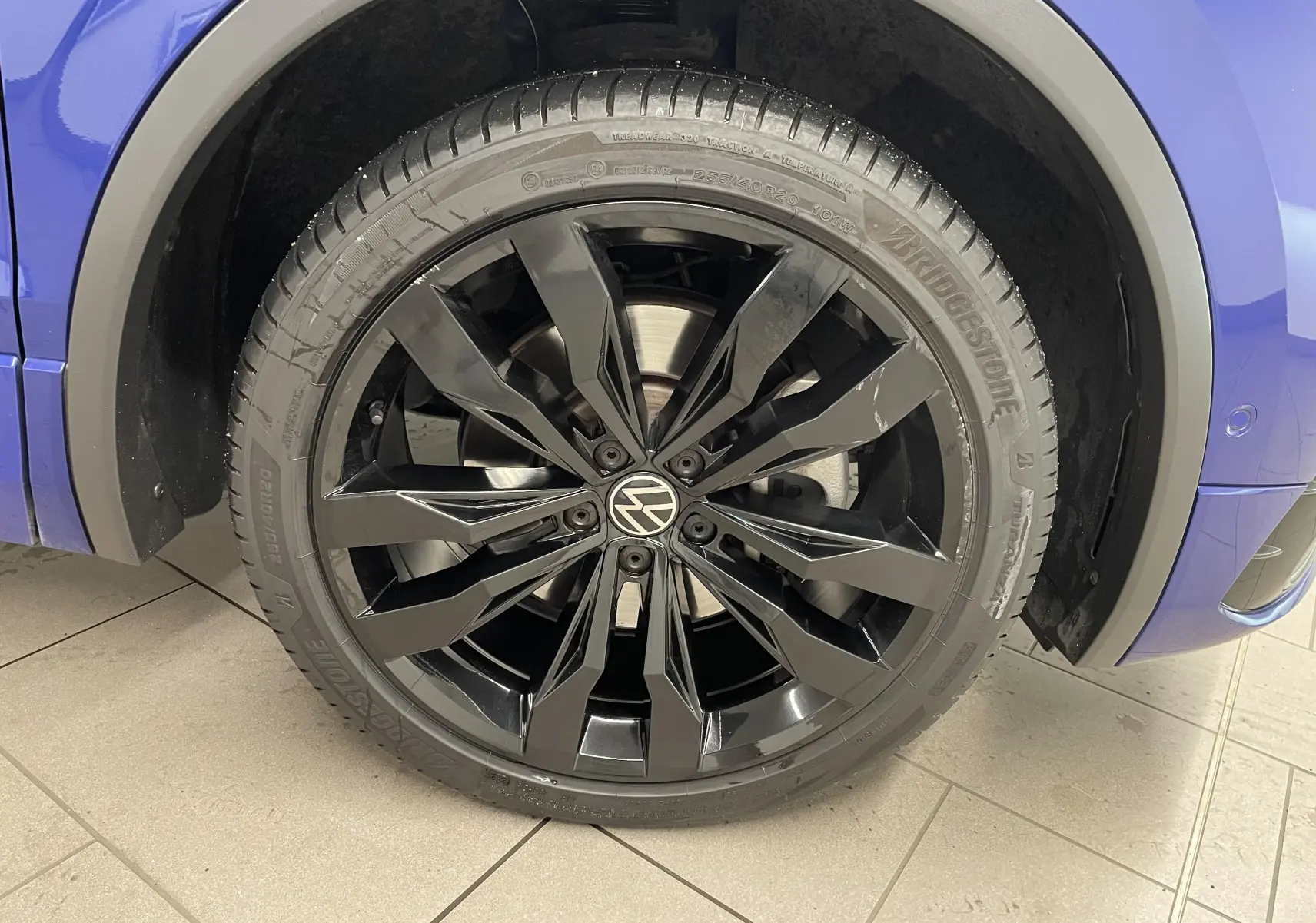 Gros plan sur la jante noire 20'' Suzuka du Volkswagen Tiguan Bleu Lapiz, avec pneu Bridgestone visible côté avant droit.