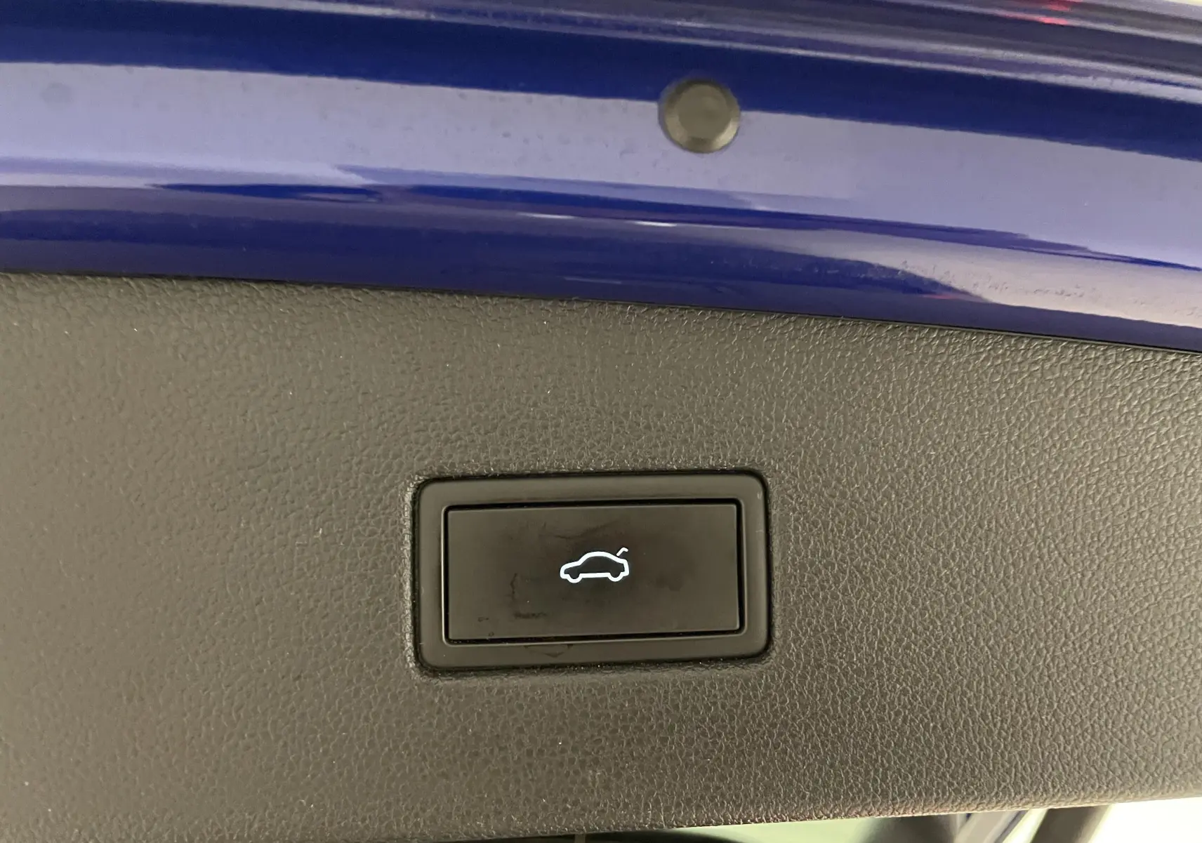 Bouton d'ouverture électrique du coffre sur la partie intérieure du hayon bleu lapiz du Volkswagen Tiguan R-Line.