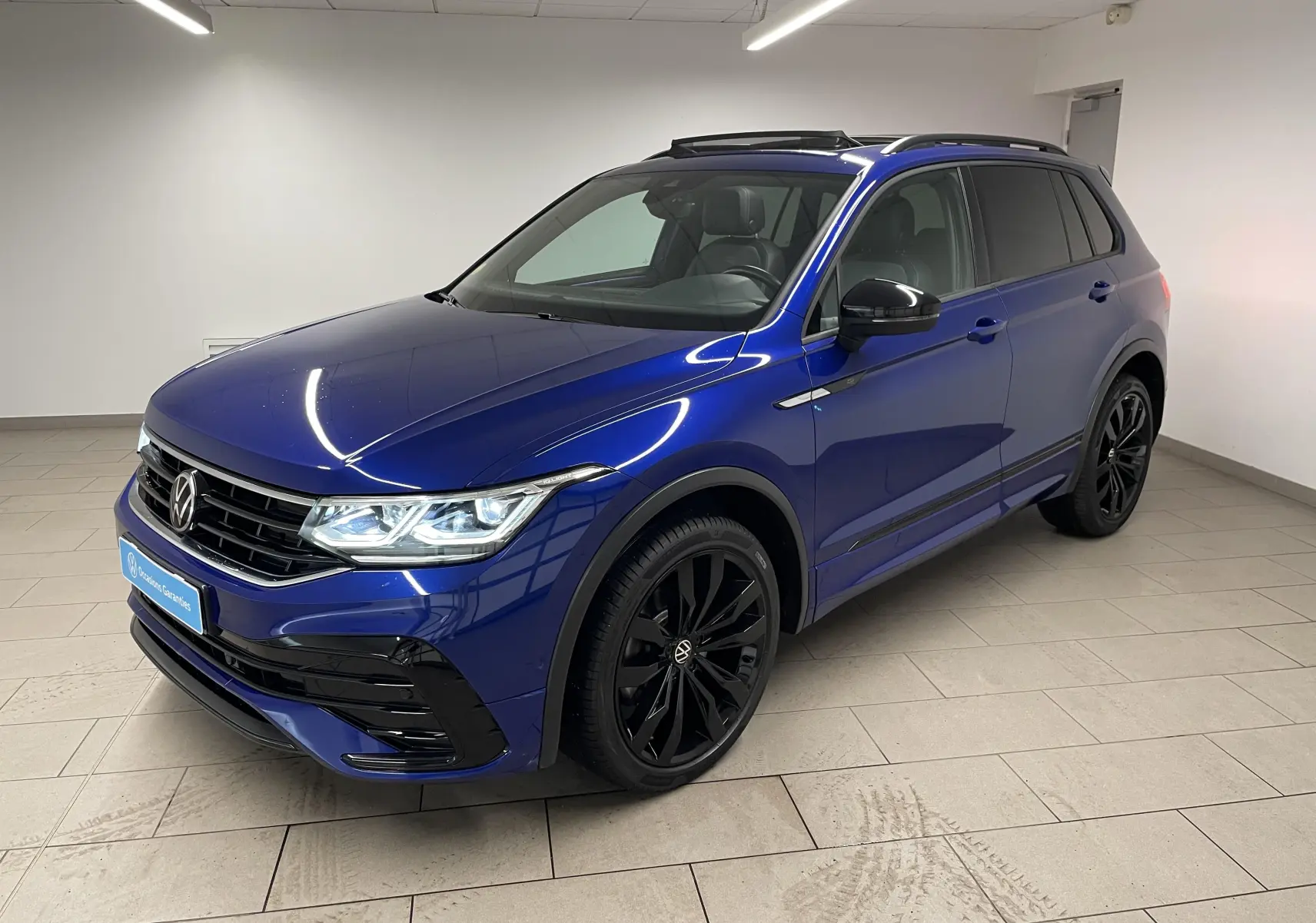 Volkswagen Tiguan 2.0 TDI 200ch 4Motion en bleu Lapiz, vue 3/4 avant avec jantes noires et toit ouvrant panoramique.