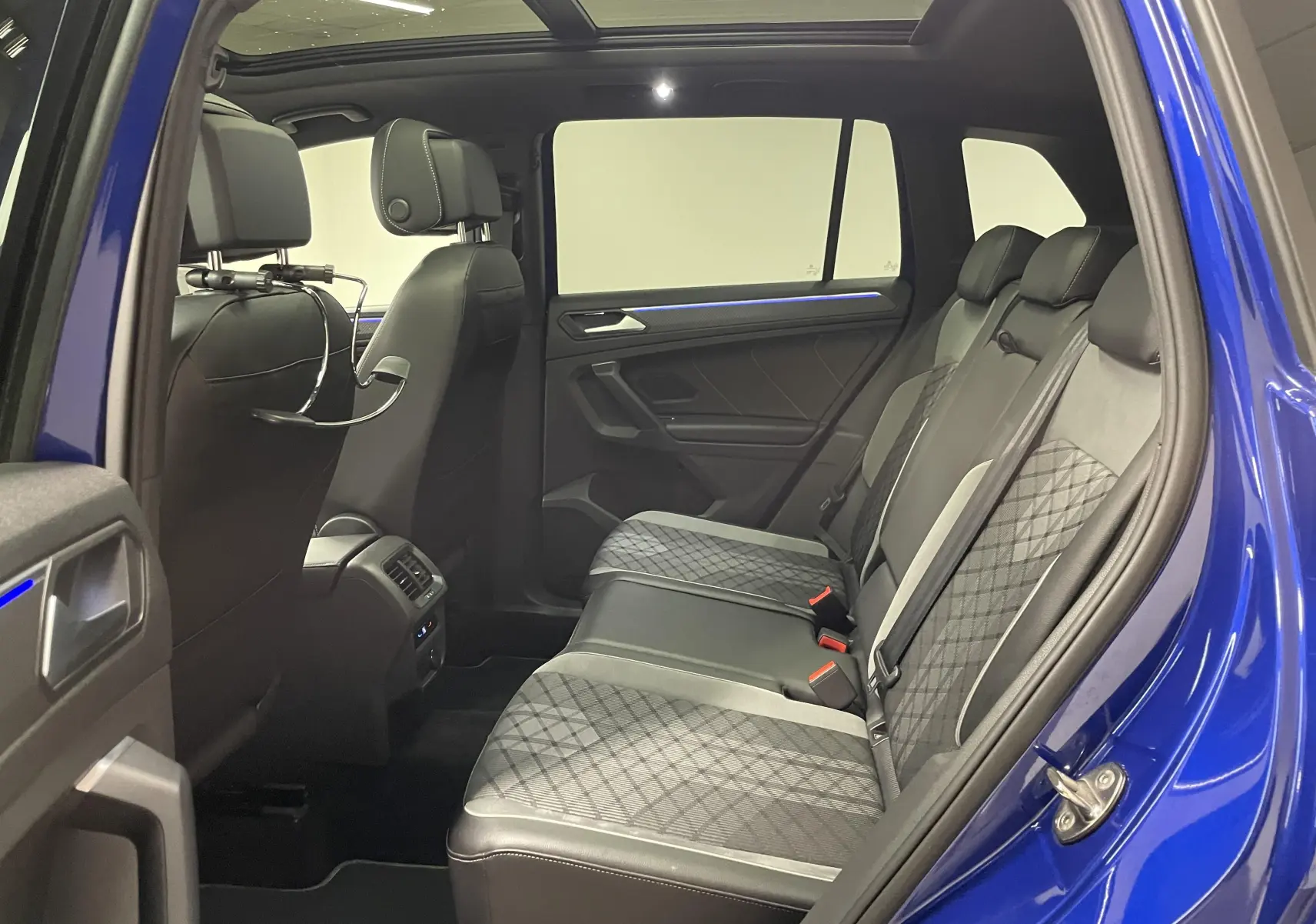 Vue intérieure côté droit des sièges arrière en tissu et cuir du Volkswagen Tiguan Bleu Lapiz avec toit panoramique ouvert.