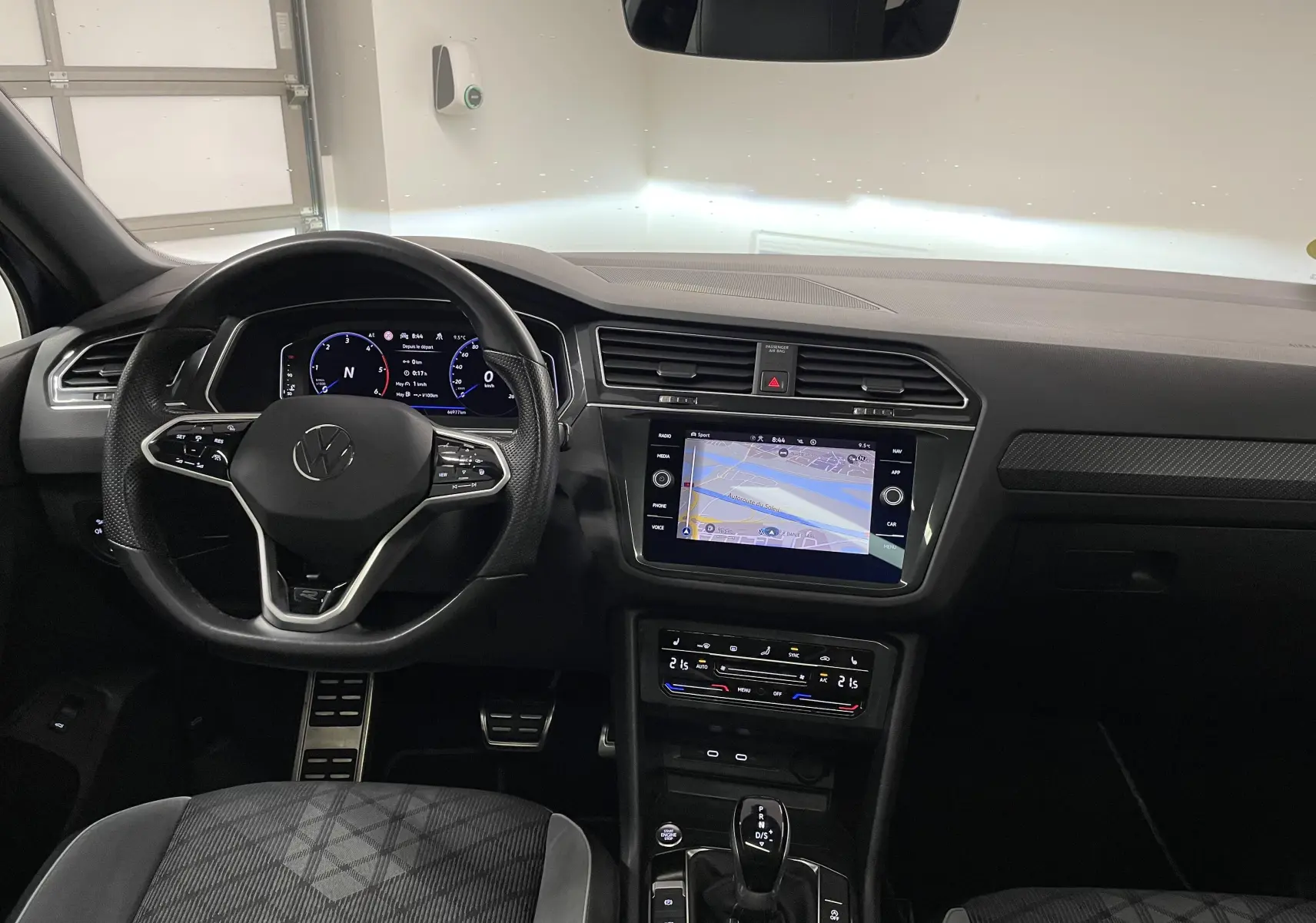 Vue intérieure avant du Volkswagen Tiguan 2022, tableau de bord noir avec écran tactile et volant multifonction.