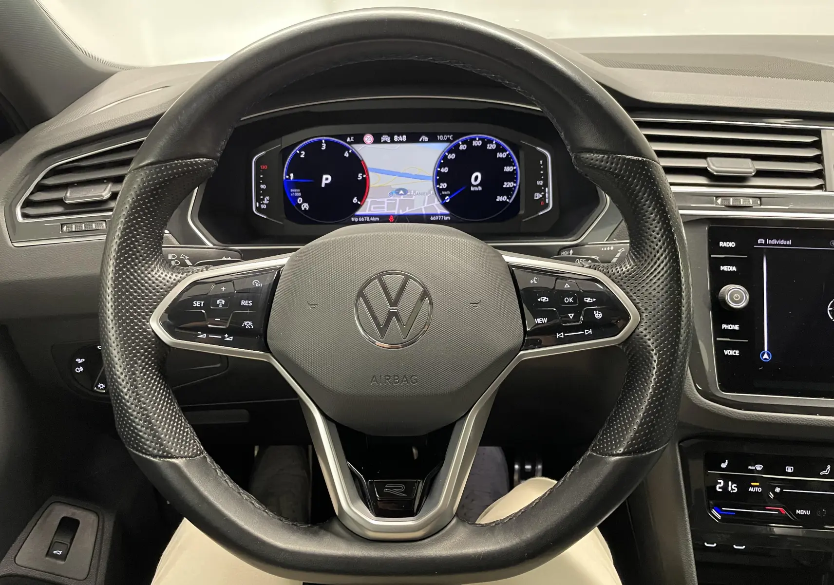 Vue intérieure centrée sur le volant cuir perforé noir et le tableau de bord numérique du Volkswagen Tiguan 2022.