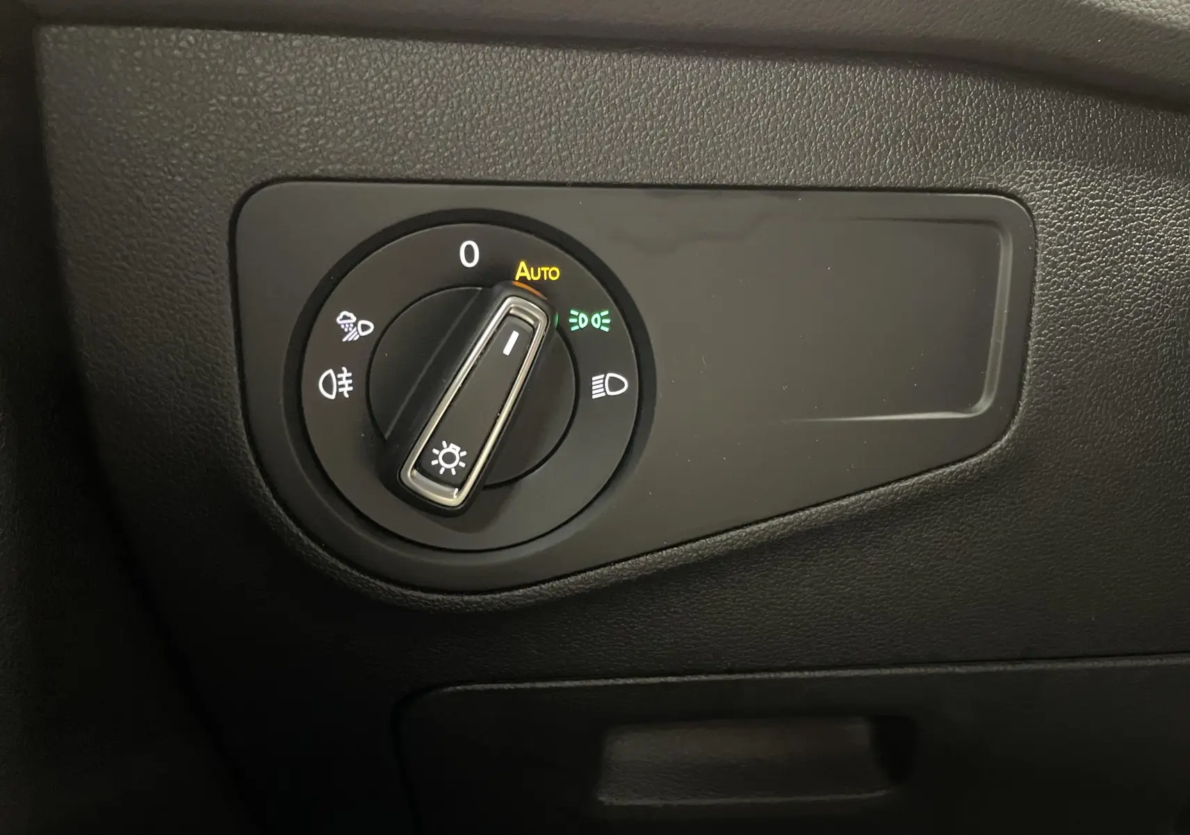 Commande des phares en gros plan sur tableau de bord noir du Volkswagen Tiguan Bleu Lapiz, version Black R-Line.