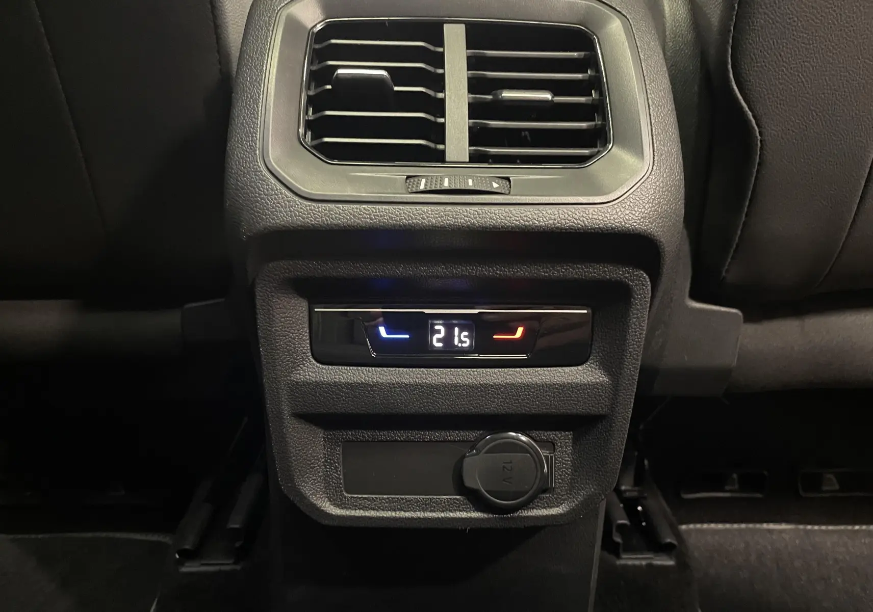 Détail de la console arrière noire du Volkswagen Tiguan 2022 avec réglage climatisation à 21,5°C et prise 12V.