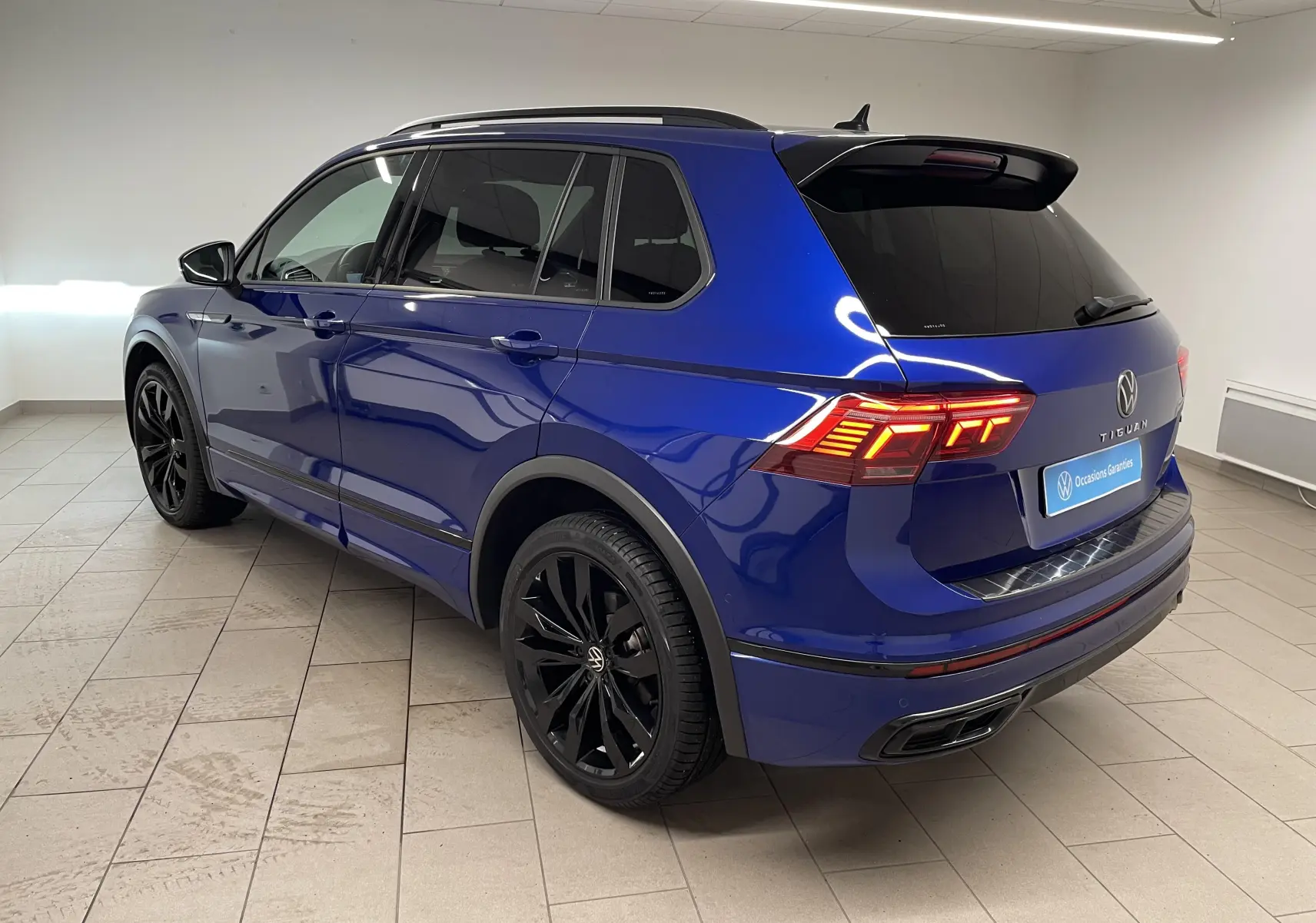 Volkswagen Tiguan 2.0 TDI 200ch DSG7 4Motion Bleu Lapiz en 3/4 arrière droit avec jantes noires et vitres surteintées.