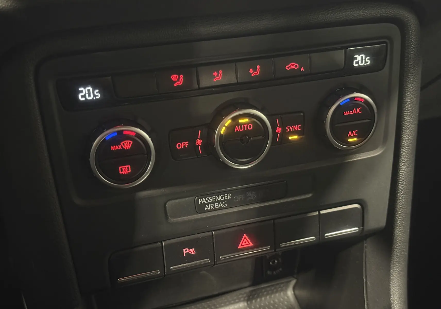 Détail du tableau de bord noir de la Volkswagen Coccinelle 2013, montrant les commandes de climatisation automatique.