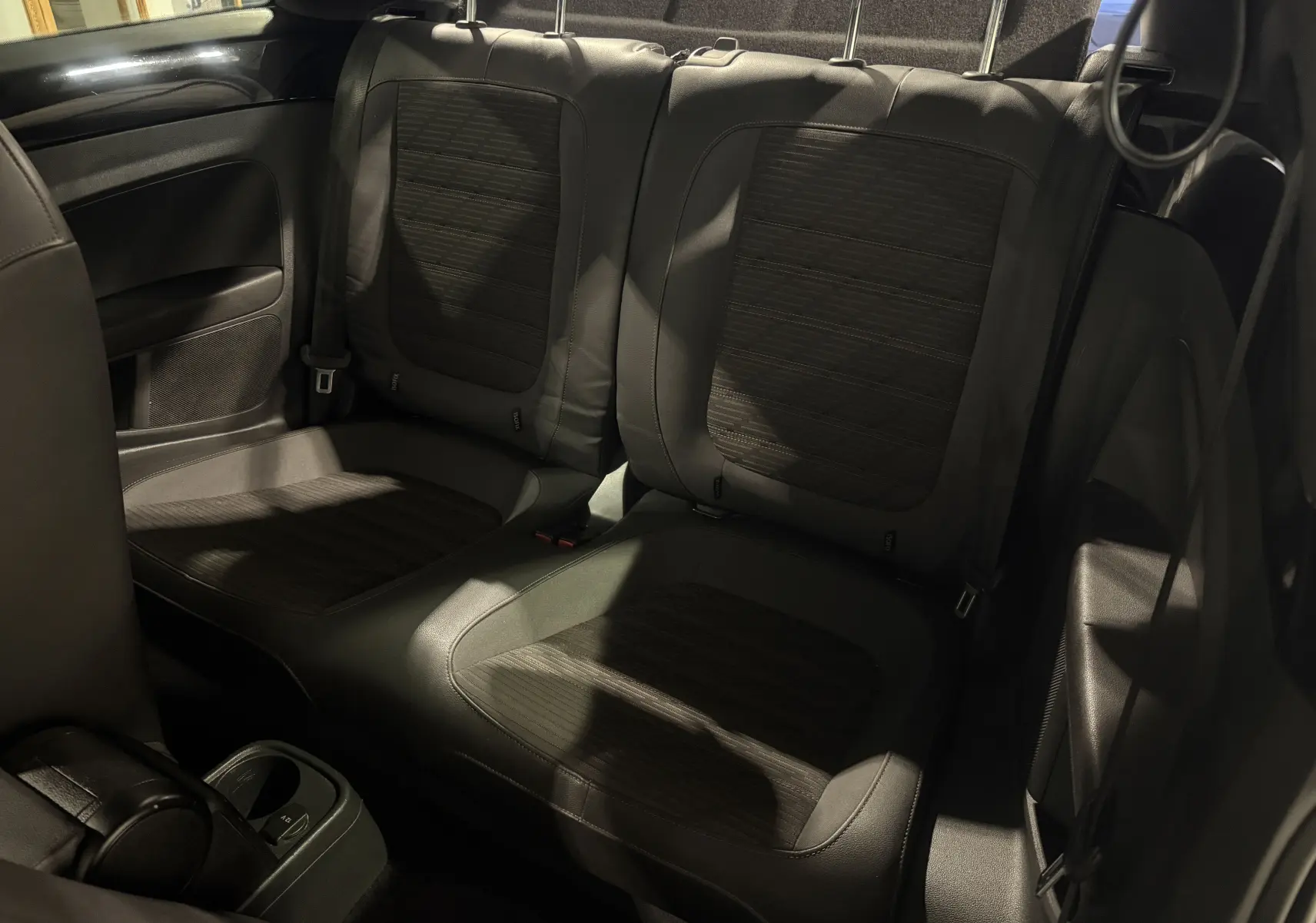 Vue intérieure des sièges arrière noirs du Volkswagen Coccinelle 1.6 TDI Fender Edition de 2013, avec finitions tissu et cuir.