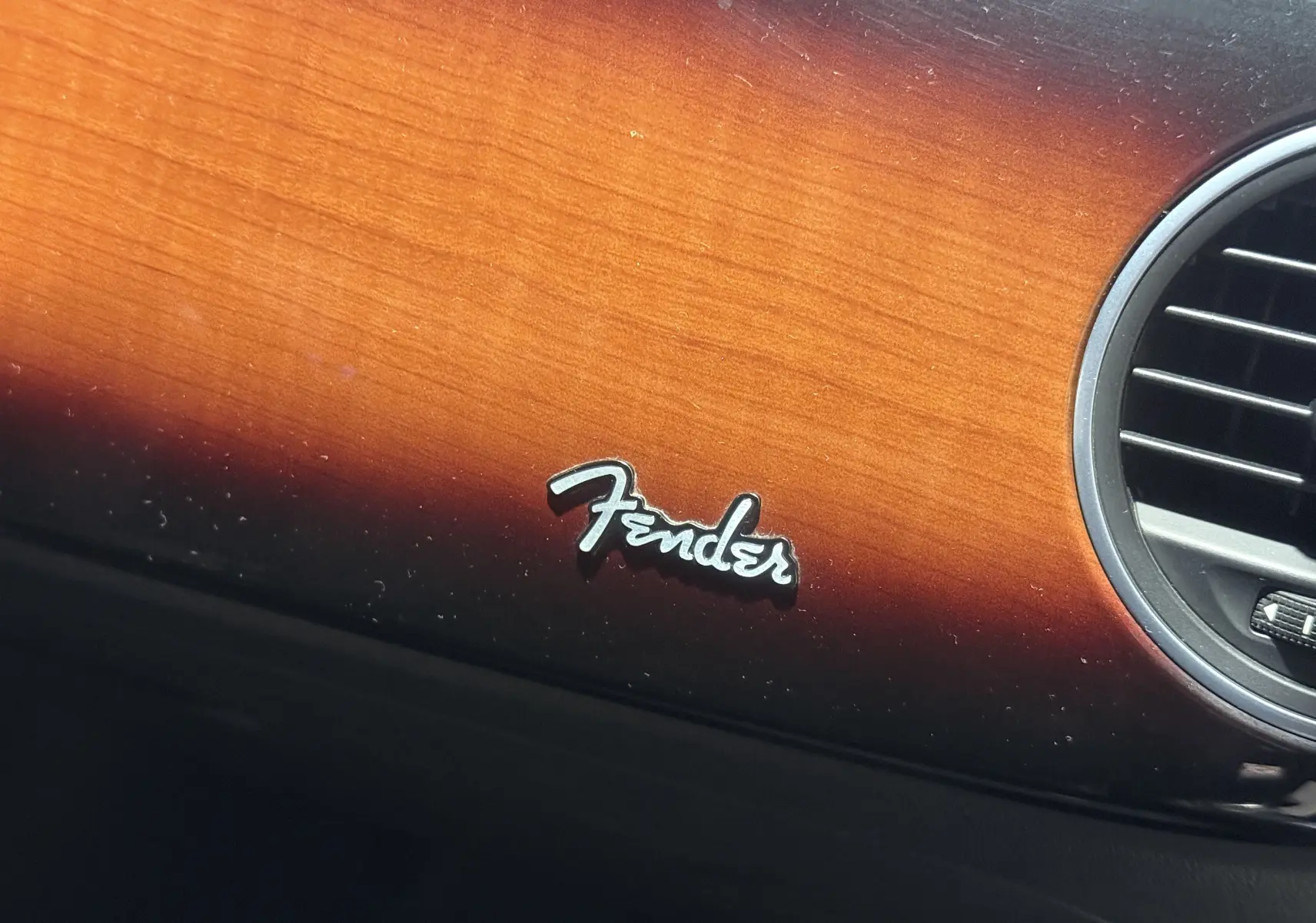 Détail du tableau de bord bois foncé avec logo Fender sur Volkswagen Coccinelle noire édition 2013.