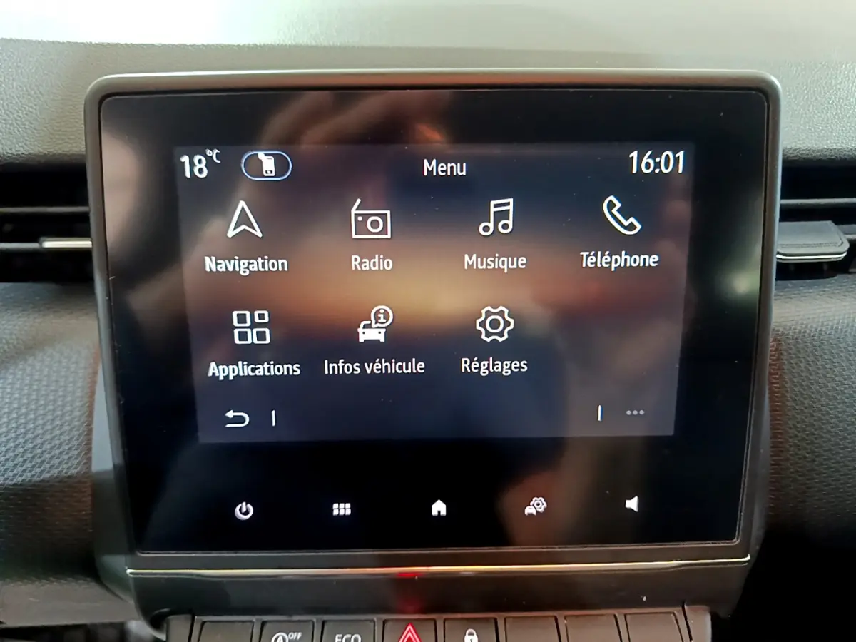 Écran tactile central de la Renault Clio Business blanc, affichant le menu principal avec icônes de navigation et musique.