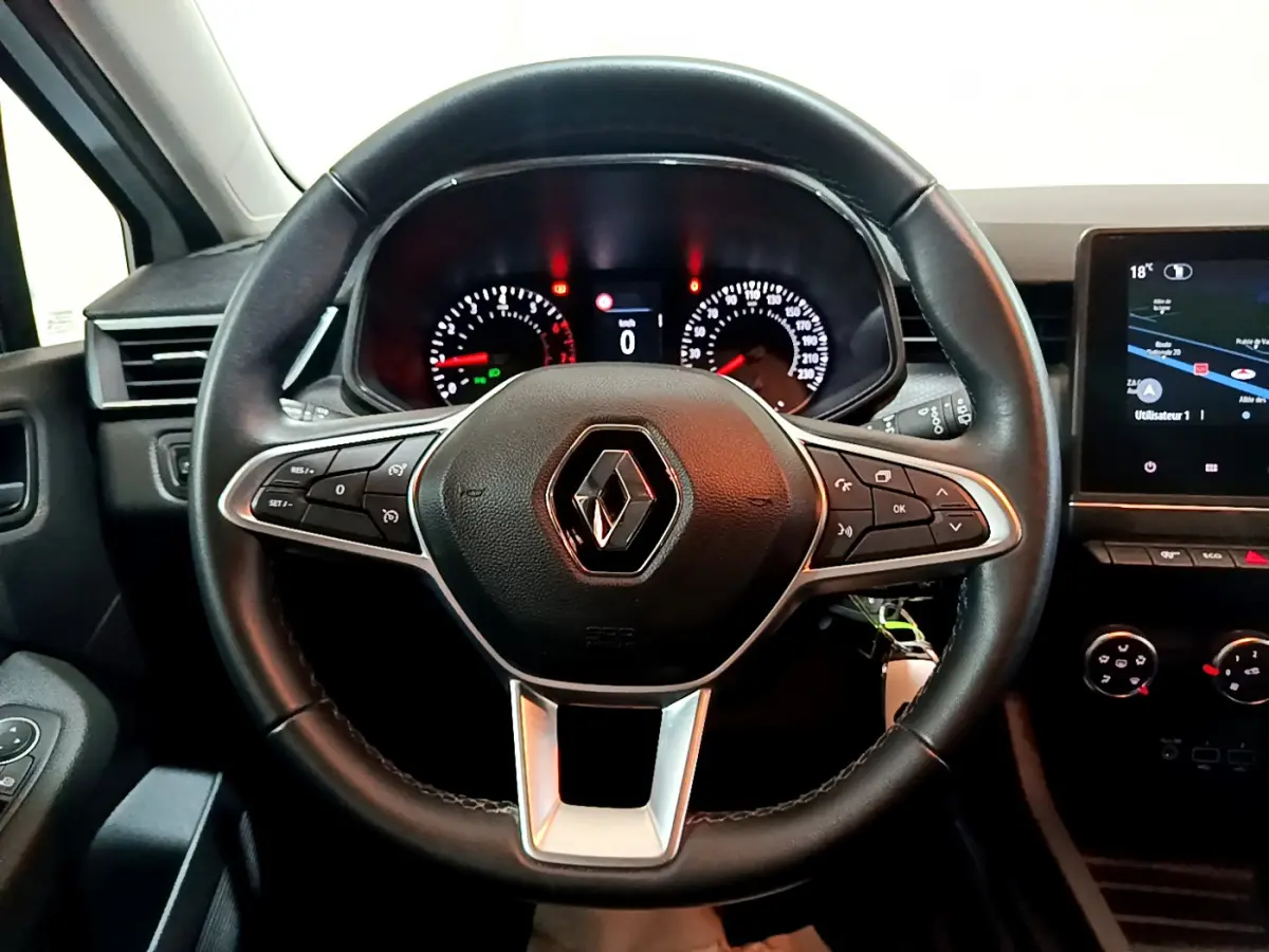 Vue intérieure centrée sur le volant cuir noir de la Renault Clio Business TCe 90 avec tableau de bord et écran tactile.