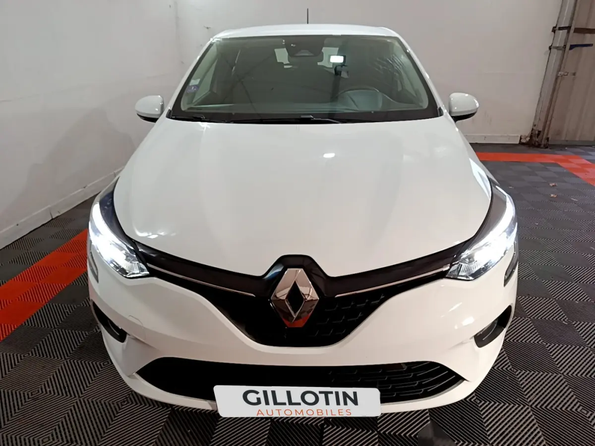 Vue avant d'une Renault Clio Business TCe 90 blanche avec phares LED allumés dans un garage.