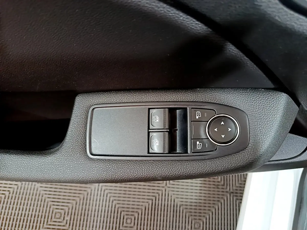 Gros plan sur les commandes de lève-vitres et rétroviseurs côté conducteur d'une Renault Clio Business blanche 2021.