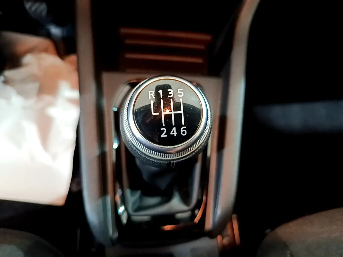 Gros plan sur le levier de vitesses manuel noir de la Renault Clio Business TCe 90 blanche, intérieur sombre.